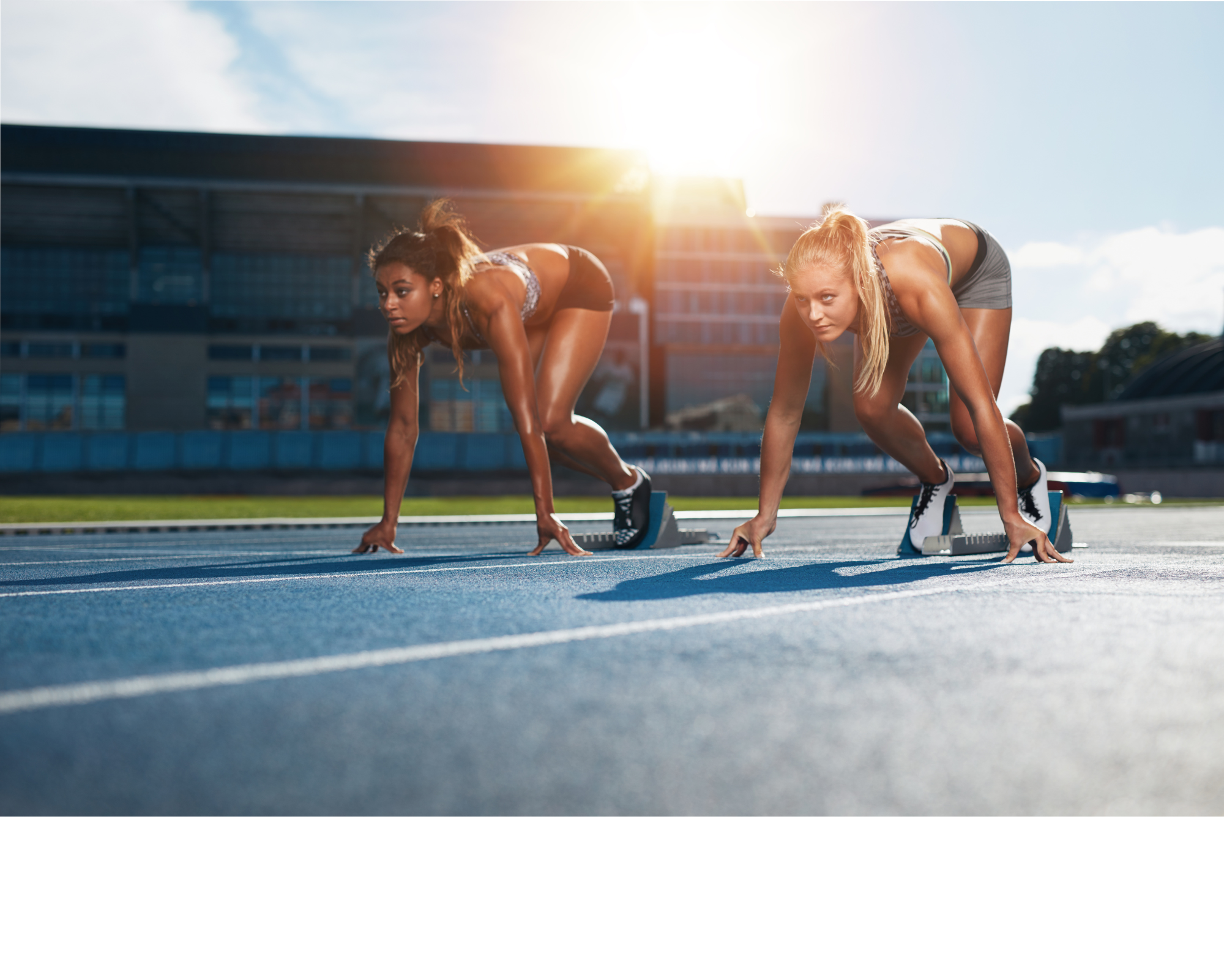 Two female track athletes setting themselves up in their blocks pre-workout